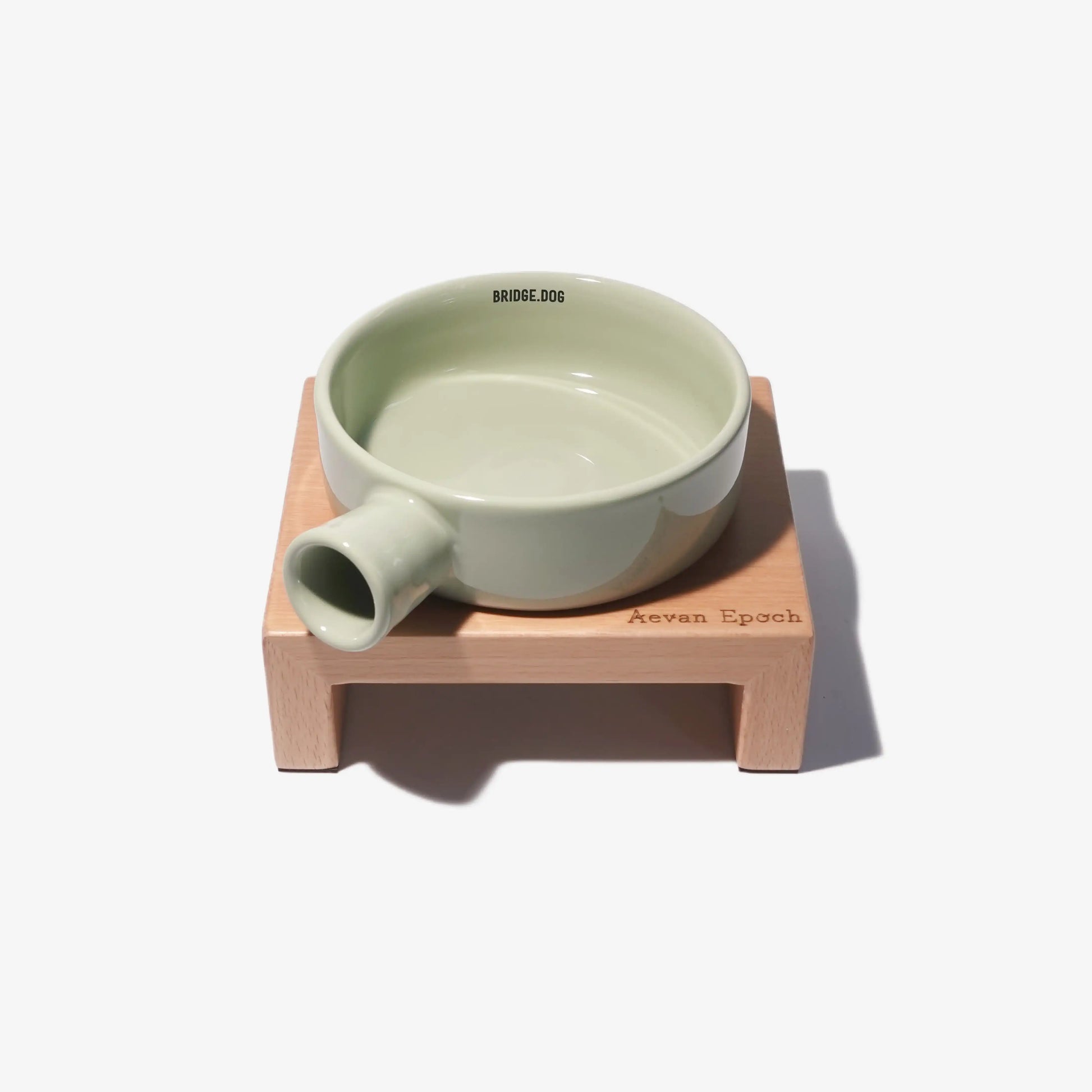 Green ceramic bowl on a wooden stand with 'Aevan Epoch' branding on a white background