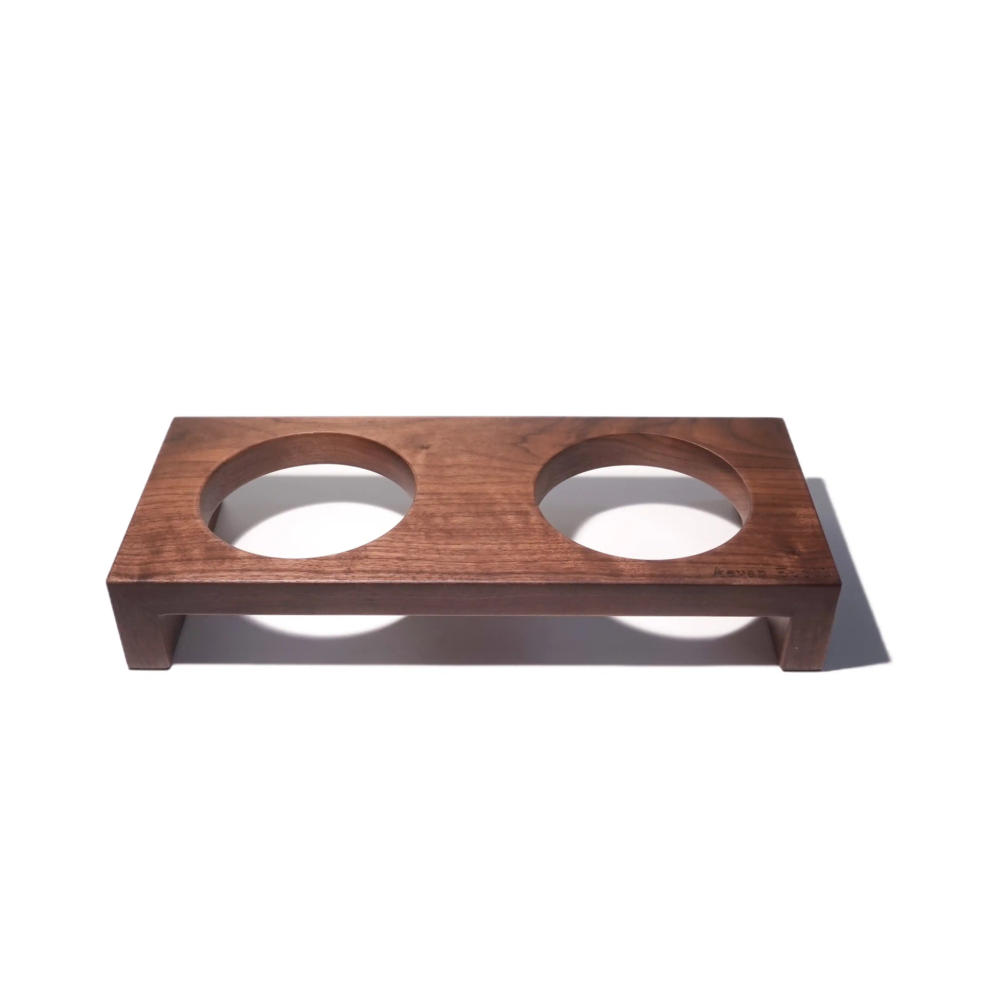 Wooden pet feeder with two circular bowls on a white background