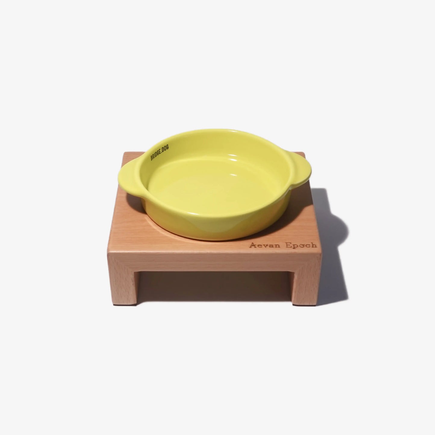 Yellow ceramic bowl on a wooden stand with 'Aevan Epoch' branding on a white background
