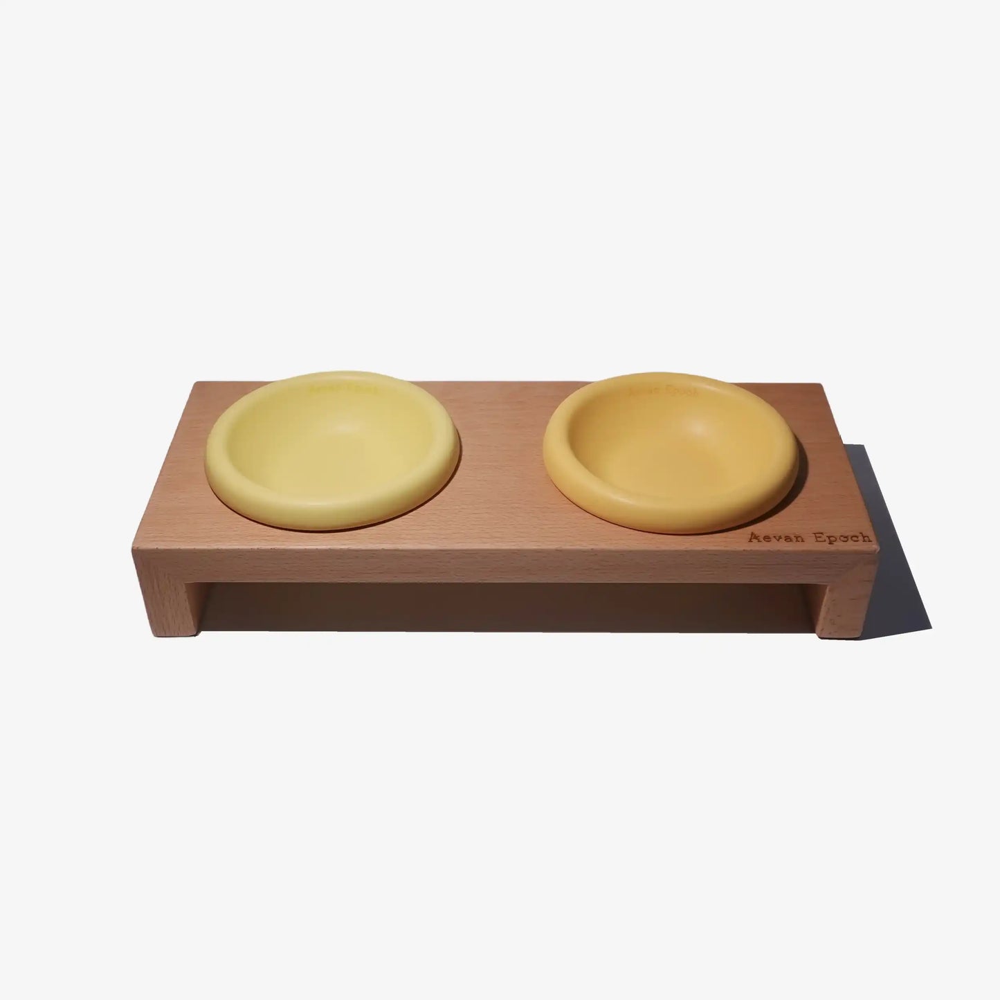 Wooden pet feeder with two yellow bowls on a white background